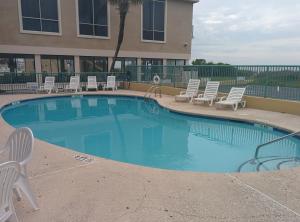 a large swimming pool with chairs and a building at Sea Dunes Oceanfront in Myrtle Beach