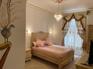 1 dormitorio con 1 cama con lámpara de araña y ventana en Chambre Lyre Maison de L'Église du Couvent en Narbonne
