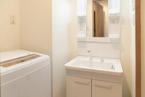 un bagno bianco con lavandino e specchio di OSAKA SUNSHINE TOWER92 ad Osaka Altre 21 foto