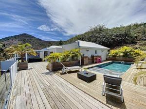 a wooden deck with a swimming pool and a house at Villa La Guapa, sea view, private pool, 5 min from the beach in Saint Martin