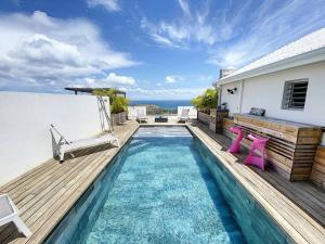 - une piscine avec une terrasse et des chaises dans une maison dans l'établissement Villa La Guapa, sea view, private pool, 5 min from the beach, à Oyster Pond