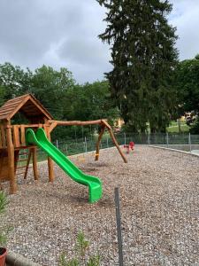 a playground with a green slide in a park at St. Hubertus Étterem és Panzió in Parádsasvár