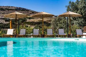 einen Pool mit Stühlen und Sonnenschirmen in der Unterkunft Anassa Cycladic Village in Galissas