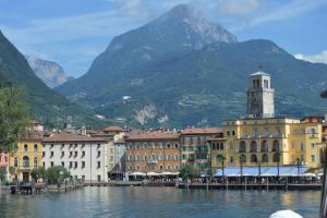 a group of buildings on the water with mountains in the background at Appartamento Sunrise - Centro Storico N2 in Riva del Garda