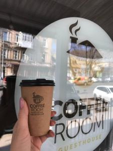 a person holding a coffee cup in front of a window at Coffee Room in Odesa