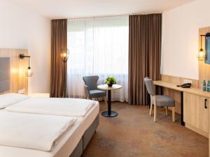 une chambre d'hôtel avec un lit, une table et des chaises dans l'établissement Plaza Hotel & Living Frankfurt, à Francfort-sur-le-Main