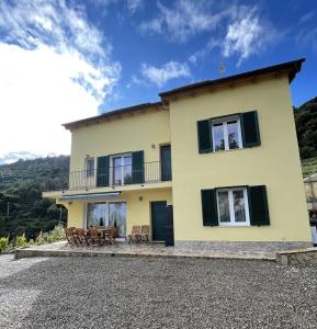 Casa amarilla grande con sillas y balcón. en Agriturismo Soleada, en Ventimiglia