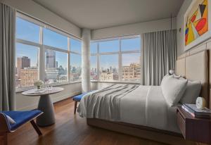 um quarto de hotel com uma cama, uma mesa e janelas em ModernHaus SoHo em Nova York