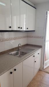 a kitchen with white cabinets and a sink at Torres Gardens-Fincas Benidorm in Benidorm +15 photos