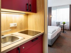 - une cuisine avec évier et un lit dans une chambre dans l'établissement Plaza Hotel & Living Frankfurt, à Francfort-sur-le-Main