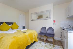 a bedroom with a yellow bed and two blue chairs at St Mary's - Modern Central Huge Studio Apartments in Southampton