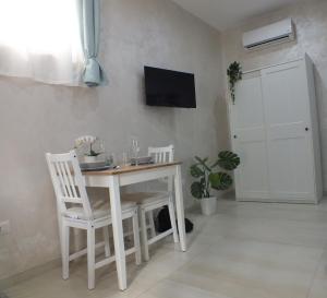 a white table and chairs in a room with a tv at B&b Ilary Home in Bari