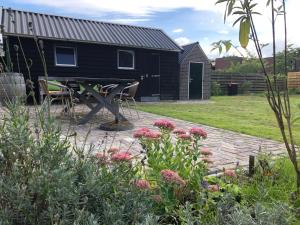 een zwart tiny house met een picknicktafel en bloemen bij Knusse vakantiewoning Valthe in Valthe