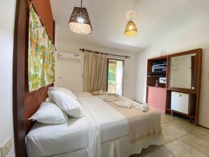 1 dormitorio con 1 cama con sábanas y almohadas blancas en Pousada Barra Velha, en Maragogi
