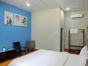 a bedroom with a white bed and a blue wall at Eden House & Coffee Con Dao in Con Dao