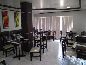 uma sala de jantar com mesas e cadeiras num restaurante em Crystal Palace Hotel em Rolim de Moura