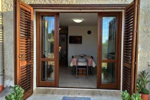 une porte coulissante en verre menant à une terrasse avec une table. dans l'établissement Casa con piscina Profumo Sea & Sun 2, à Triscina