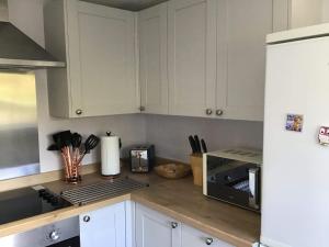 a kitchen with white cabinets and a white refrigerator at 3 Knocknaha Cottage in Campbeltown