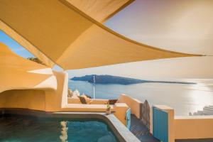 a house with a swimming pool and a view of the ocean at Nano Oia Villas in Oia