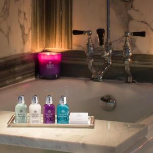 a bathroom sink with four bottles of soap and a candle at Unicorn Hotel in Llanidloes