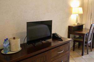 a table with a television and a coffee mug on it at Hotel Villa Therese in Port-au-Prince