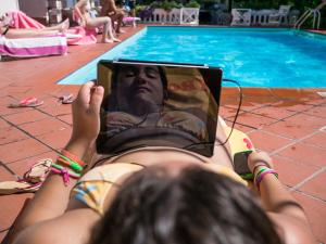 Eine Frau auf einem Stuhl mit einem Buch auf dem Gesicht in der Unterkunft Hotel Apis in Rimini