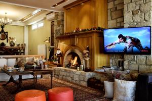 ein Wohnzimmer mit einem Kamin und einem Flachbild-TV in der Unterkunft Luxurious Villa by the sea in Posidhonía