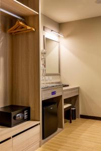 baño con espejo, lavabo y microondas en San Chiao Hotel en Dazi