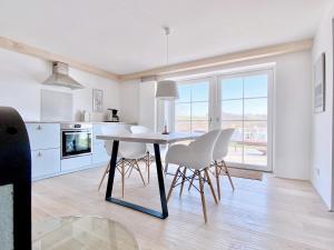 a white kitchen with a dining table and chairs at See 11 in Harrislee