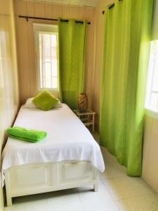 1 dormitorio con cama blanca y cortinas verdes en Tropical Coral, en San Andrés