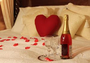 Una botella de vino y copas en una cama con corazón en Colston Hall Farmhouse B&B en Framlingham