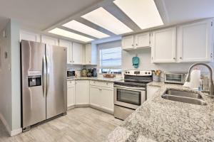 a kitchen with white cabinets and a stainless steel refrigerator at Cape Canaveral Escape with Grill Walk to Beach! in Cape Canaveral