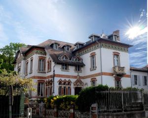 una gran casa blanca con una valla delante en La Maison d'hôtes du Chapelier, en Espéraza