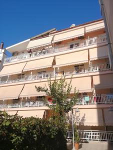 un edificio de apartamentos con balcones blancos y un árbol en Villa Vienni, en Paralia Katerinis