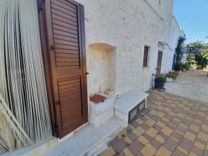 une porte en bois avec un banc à côté d'un bâtiment dans l'établissement CASA BALICE, à Monopoli