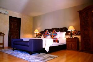 a bedroom with a large bed and a blue chair at Hotel Real de Minas Tradicional in Querétaro