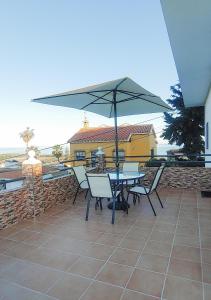 stół i krzesła z parasolem na patio w obiekcie Villa del Carmen w mieście Almayate Alto