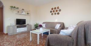 uma sala de estar com duas cadeiras e uma televisão em Villa del Carmen em Almayate Alto