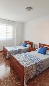 a bedroom with three beds with blue pillows at Villa del Carmen in Almayate Alto