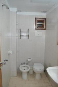 Baño blanco con aseo y lavamanos en Hotel Montecarlo en Villa Gesell