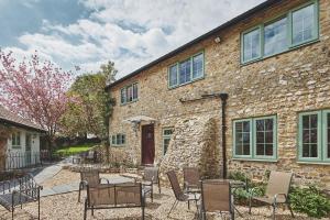 a stone building with chairs and a table in front of it at Blackdown Cottage in Stockland