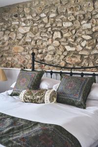 a bed with two pillows and a stone wall at Blackdown Cottage in Stockland