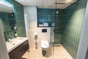 Baño de azulejos verdes con aseo y lavamanos en Boutique Hotel Zaan en Zaandijk