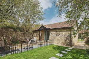 a stone house with a fence in the yard at Harcombe Cottage in Stockland