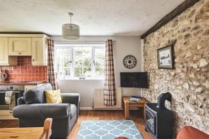 a living room with a couch and a stone wall at Harcombe Cottage in Stockland