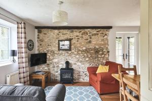 a living room with a couch and a stone wall at Harcombe Cottage in Stockland