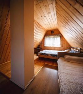 a attic room with two beds and a window at Gravas dzirnavas in Dārznieki
