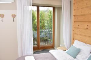 a bedroom with a bed and a large window at Apartament Erica in Zakopane