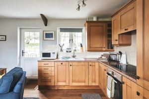 a kitchen with wooden cabinets and a sink at Half Moon Cottage in Stockland