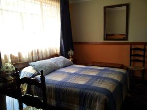 1 dormitorio con cama, ventana y espejo en Hotel Colomba, en Huaraz